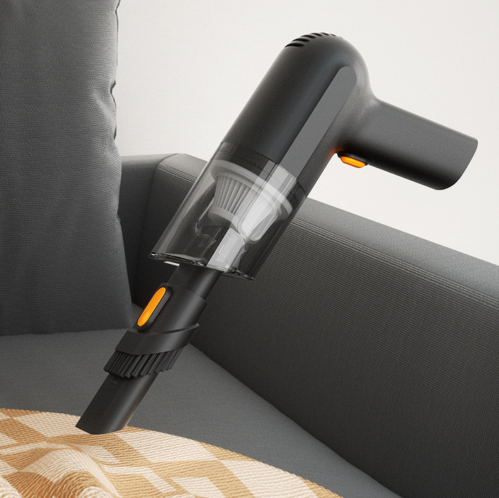 Black cordless handheld vacuum with a clear dust cup pictured beside a sofa.